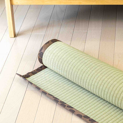  brown tatami Ando rolled on wooden floor in front of a sofa