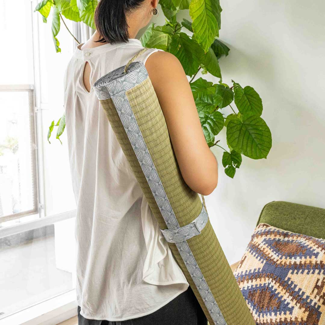 woman carrying a gray colour Japanese tatami roll on her right shoulder