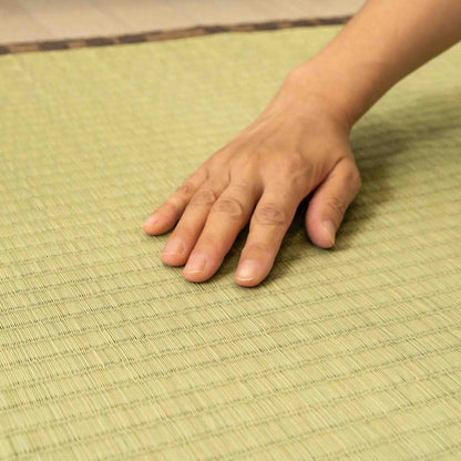 woman's hand's touching a brown tatami Ando placed on the floor.