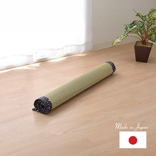 a roll tatami mat on a wooden floor next a plant