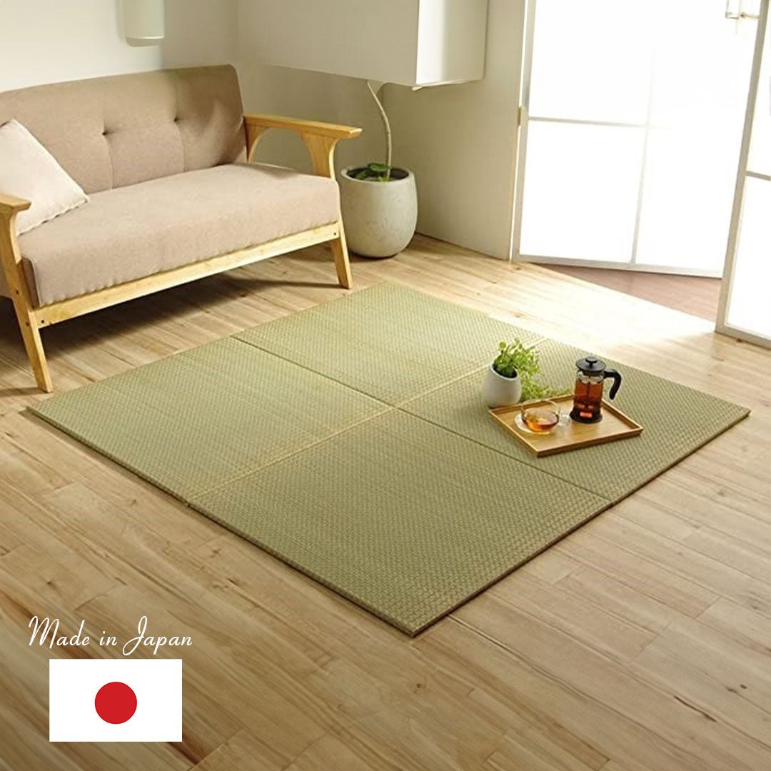four square tatami mat in a living room with a sofa next to it and an open window a tea set on the tatami