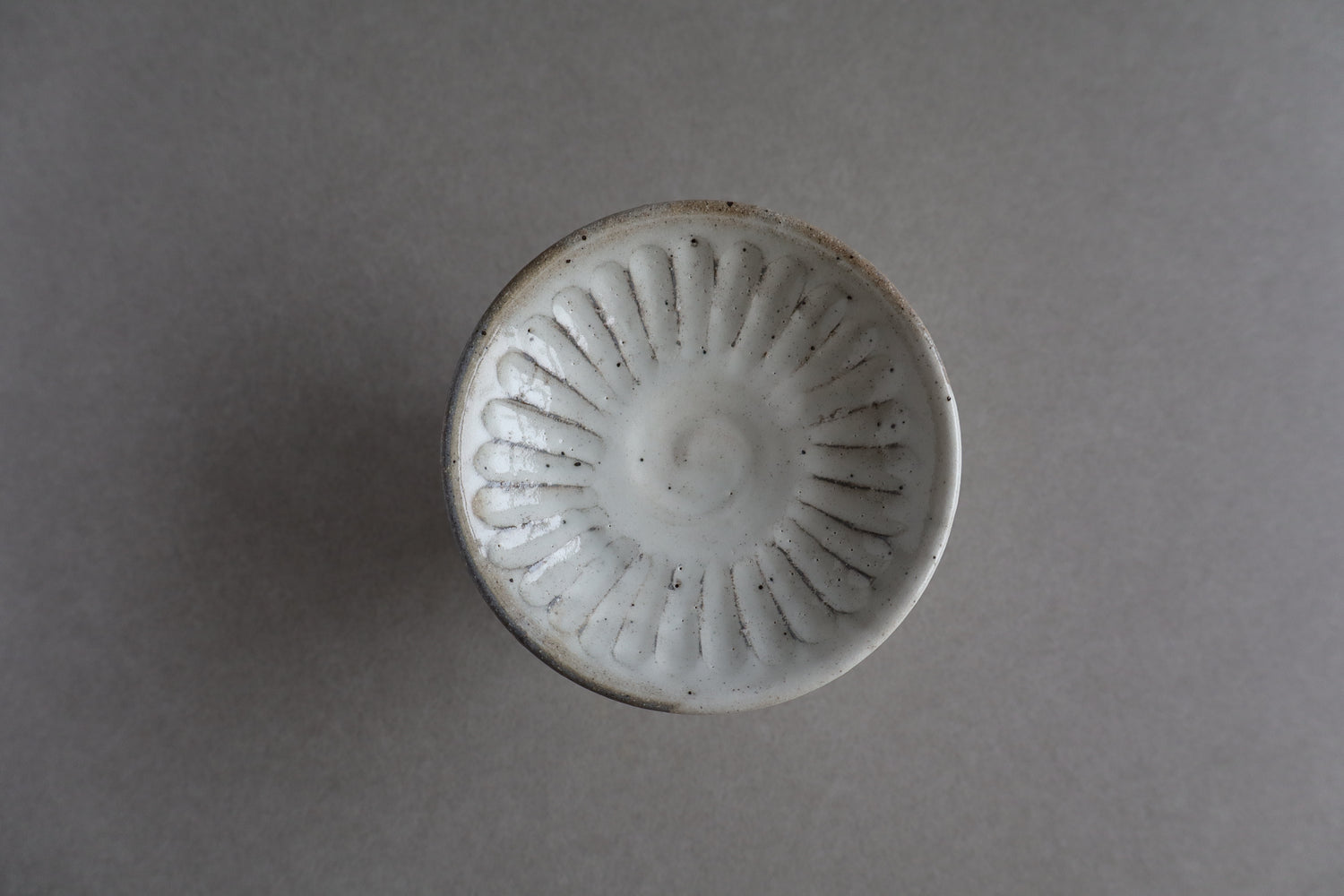 White ceramic knob with decorative pattern on a gray background