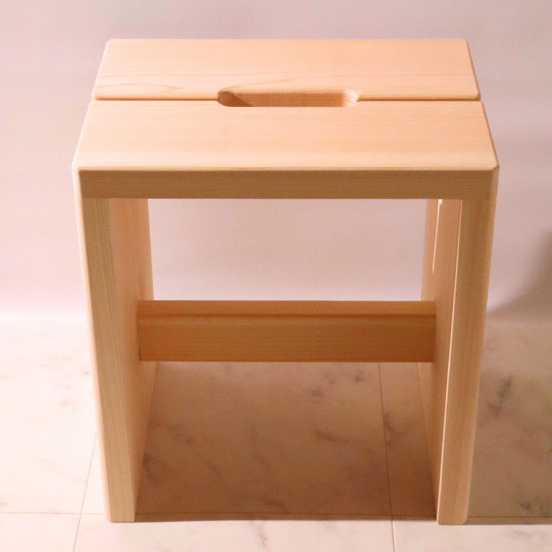 Wooden stool with a handle on a light-colored floor.
