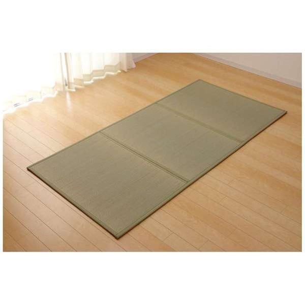 A Japanese tatami mat lies on a hardwood floor near a sunlit window, enhancing the serene and minimalistic aesthetic of the room.