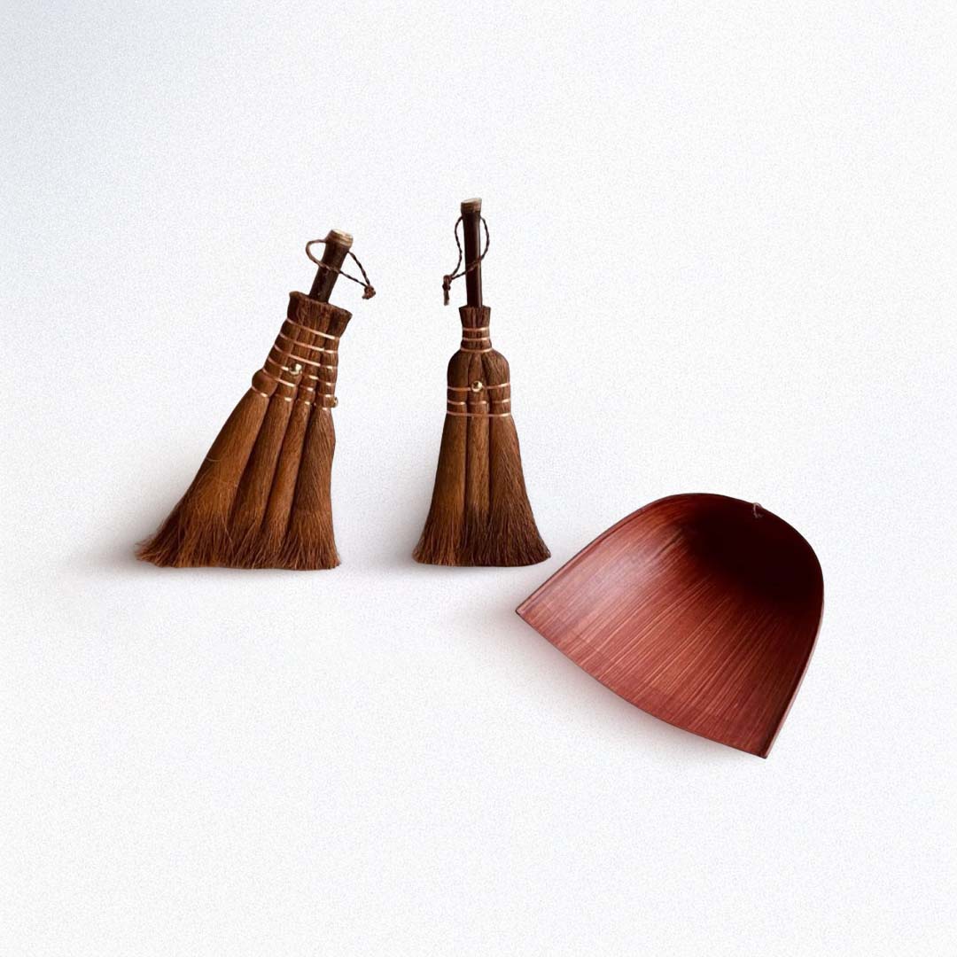 Two wooden brooms and a wooden dustpan on a white background