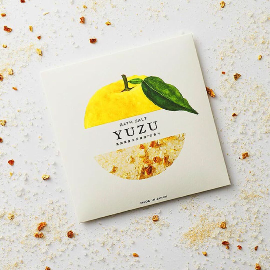 Yuzu bath salt package on a textured surface with yuzu fruit illustration