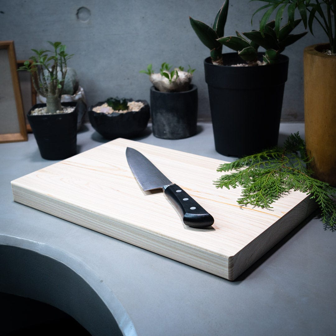 wooden cutting board with a knife and leaf on it in a japanese kitchen surrounded by plants