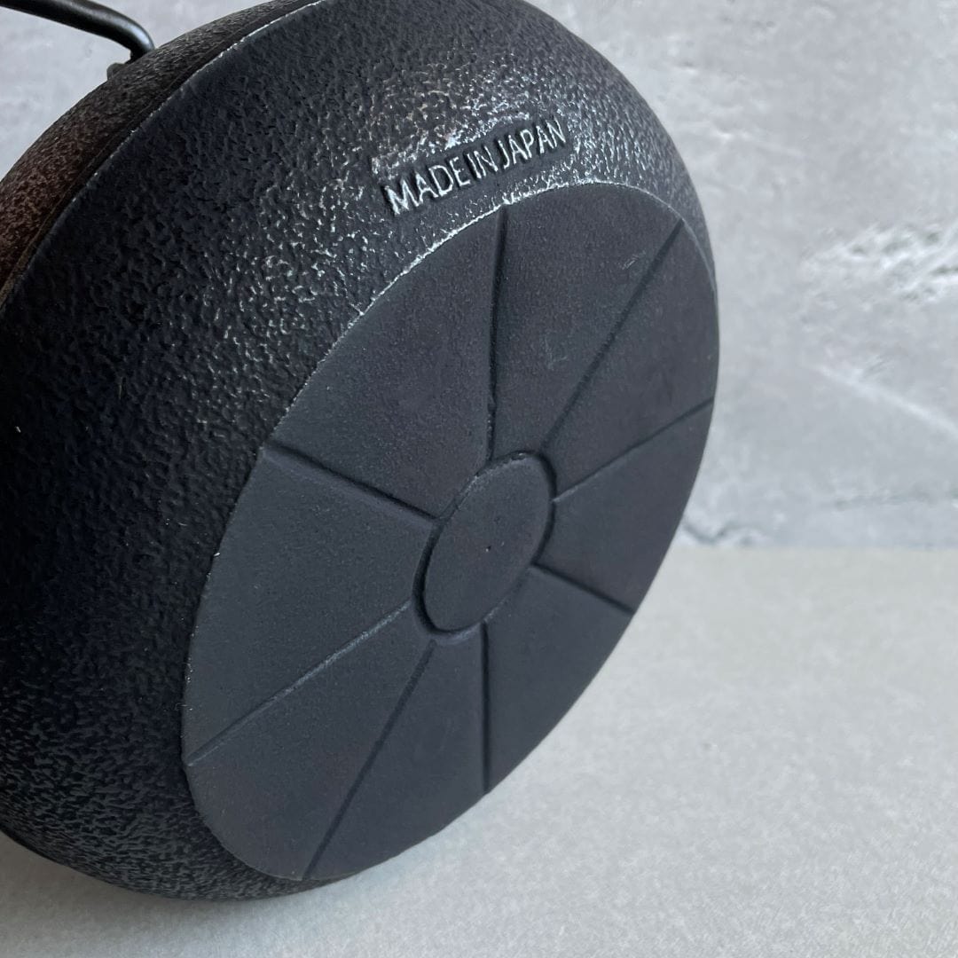 This is the back side of a Japanese cast iron kettle, with a smooth surface. At the top of the kettle, &quot;Made in Japan&quot; is written in visible text.