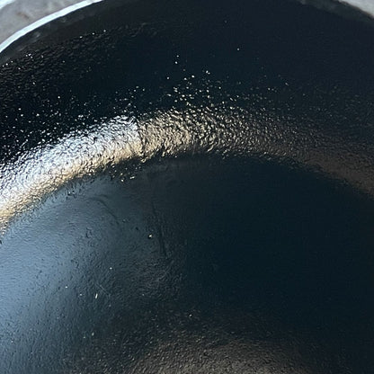 This is a close-up inside view of a black cast iron Tetsubin kettle, with an enameled interior. The surface appears smooth and glossy, and the image is taken from the side of the kettle.