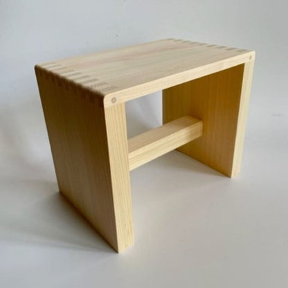 upper view on a wooden square stool in a grey room