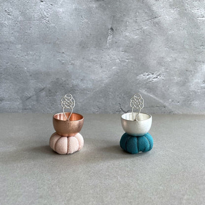 Two singing bell one pink color and one blue  on a grey room