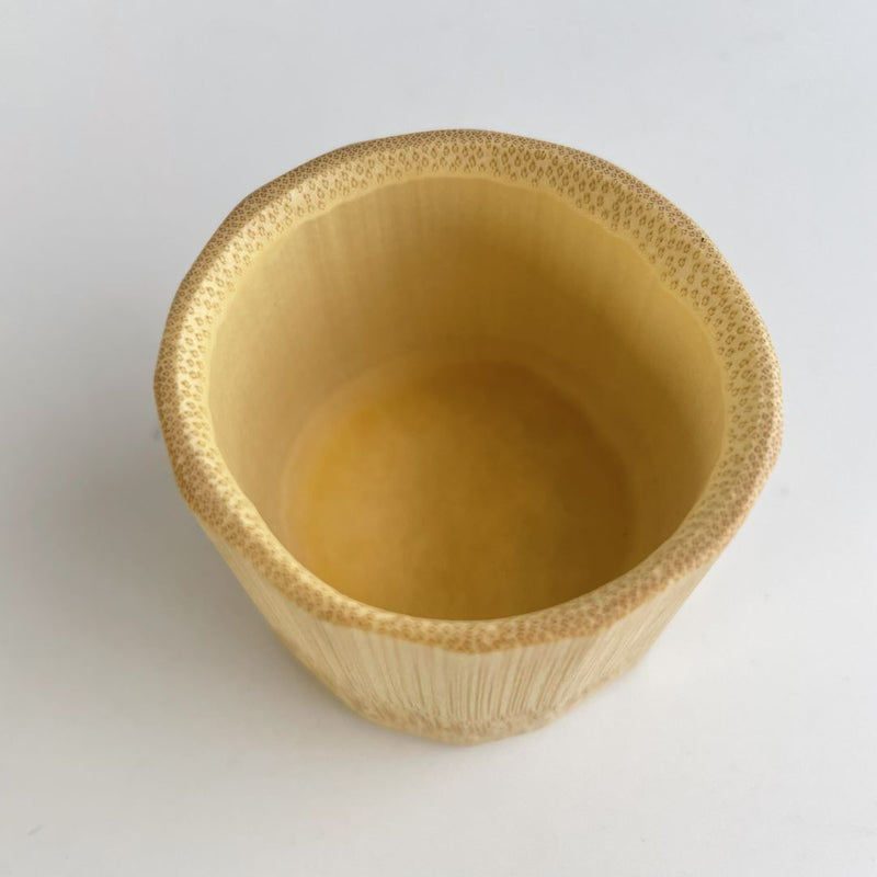 A top-down view of a bamboo sake cup with a smooth finish, placed on a flat surface.