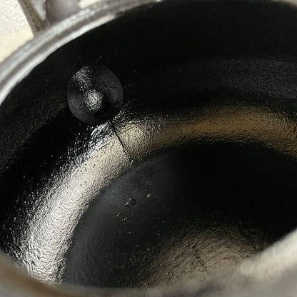 This is a close-up inside view of a black cast iron Tetsubin kettle, with an enameled interior. The surface appears smooth and glossy, and the image is taken from the side of the kettle.