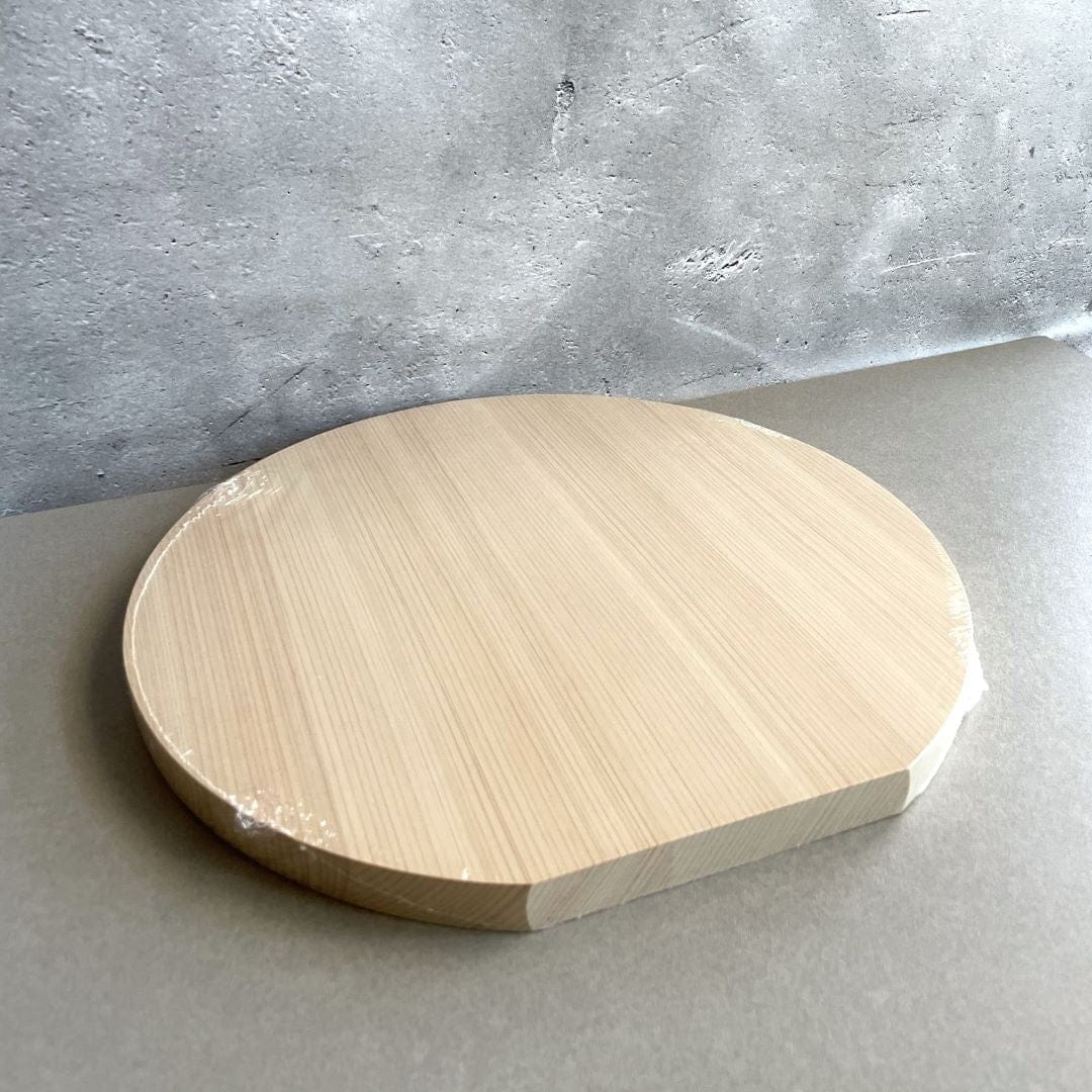 a wooden cutting board on a grey table next to a concrete wall