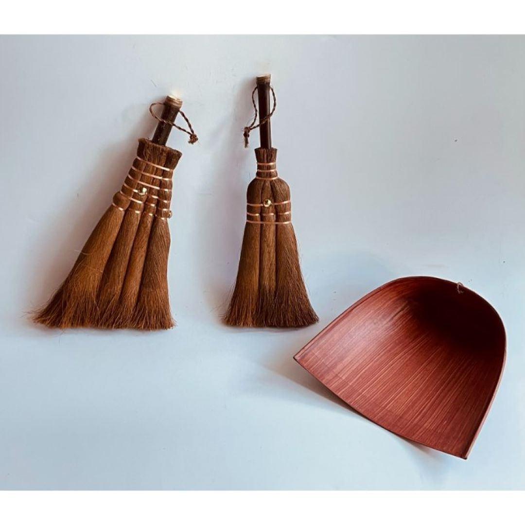 Two brown whisk brooms made of hemp and bamboo with brown dustpan in a grey background