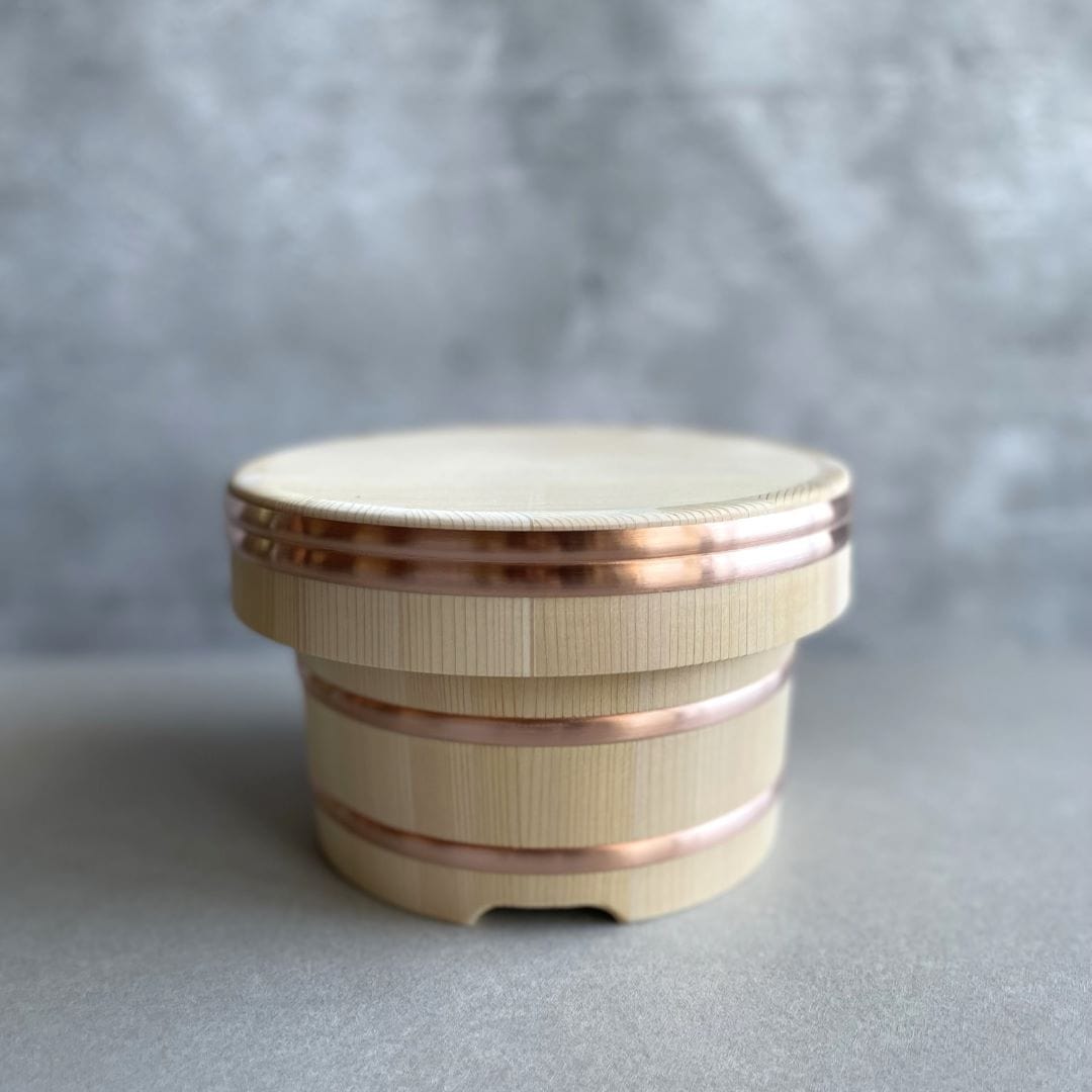 a wooden rice container with copper on a grey background put on a grey table