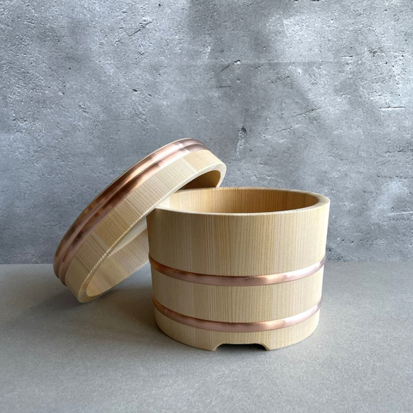 A wooden rice container with open lid on a grey background on a grey table.